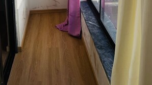 A narrow hallway with a wooden floor, a window with a black frame, and a purple curtain. - Cozy 2-bedroom Apartment in Pontinha, Portugal (Amadora)