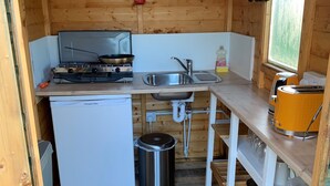 Une cuisine de taille réduite, équipée d’une cuisinière, d’un évier et d’un petit réfrigérateur.