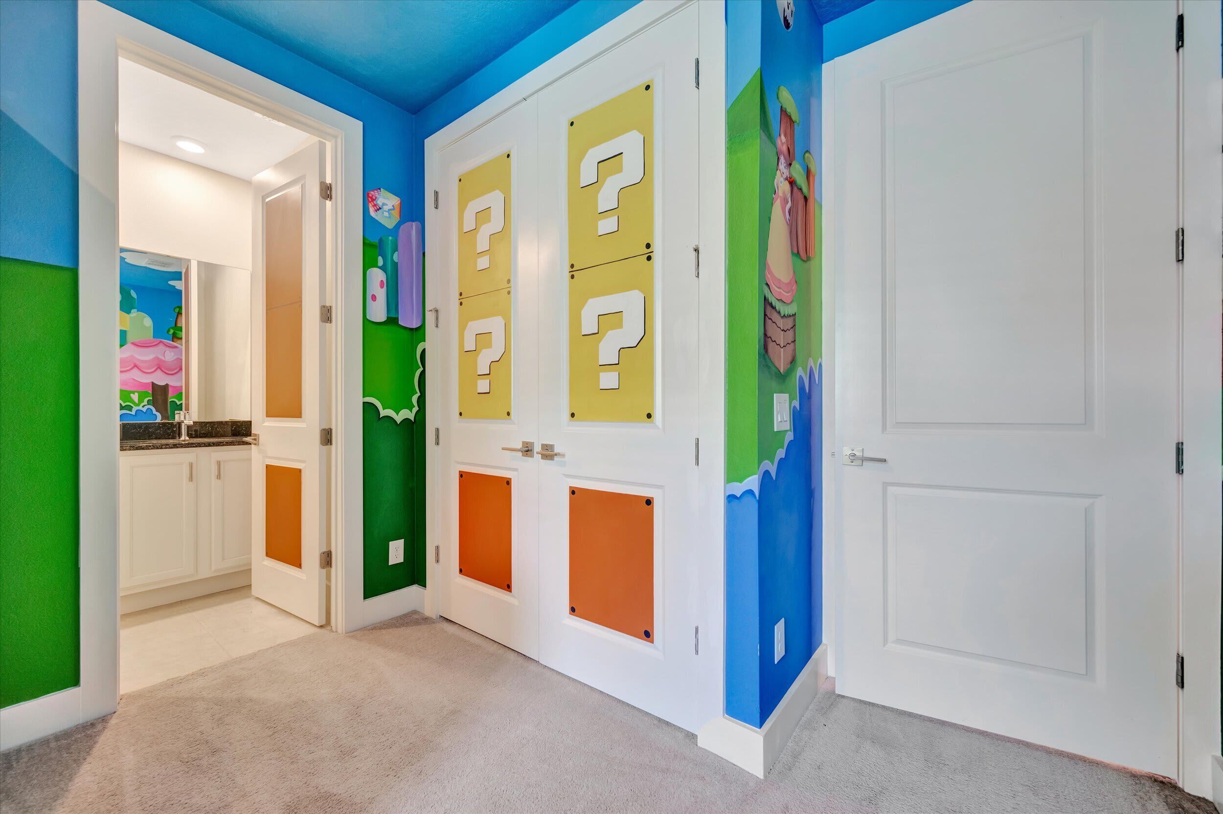 Un pasillo con paredes de colores, una zona de cocina y una puerta blanca.
