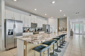 Your chef's kitchen awaits with gleaming granite countertops, stainless steel appliances, and a spacious island with seating—perfect for gathering over morning coffee or evening meals together. - Reunion Resort: 8-Bed Villa, Arcade, Theater, Pool (Kissimmee)