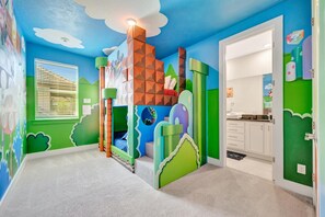 Your little ones will love this vibrant, imaginative bedroom themed like a classic video game world—complete with pixelated clouds on the ceiling and a cozy castle-themed bed tucked into the corner. - Reunion Resort: 8-Bed Villa, Arcade, Theater, Pool (Kissimmee)