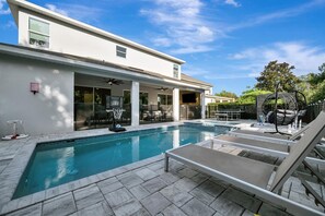 Step outside to your private backyard paradise—a sparkling pool framed by modern loungers and lush Florida greenery, perfect for relaxing under the sun or unwinding in the shade. - Reunion Resort: 8-Bed Villa, Arcade, Theater, Pool (Kissimmee)