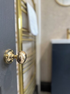 A door with a brass doorknob, a towel hanging on a radiator, and a dark-colored cabinet in the background.