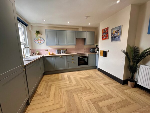 A kitchen with grey cabinets, a herringbone floor, a microwave, and a sink.