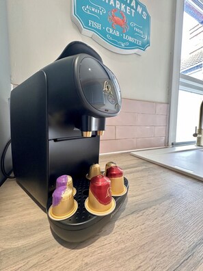 A coffee machine with four cups, a sign above it, and a window in the background.