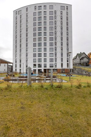 A modern building with a curved facade, multiple windows, and a playground area in front. - The View - City center apartment with spectacular views (Tromsø)