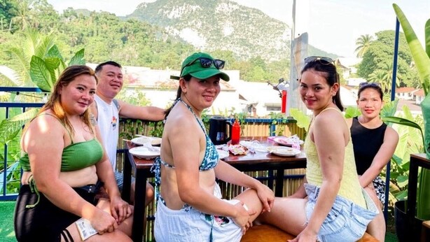 Un grupo de personas sentadas en una mesa al aire libre con vista a un paisaje montañoso.