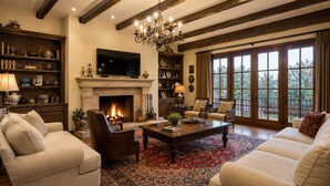 A living room with a fireplace, sofas, a coffee table, and a chandelier. - Sunset aparts (Tbilisi)