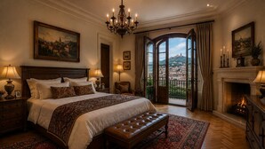 A spacious bedroom with a large bed, a fireplace, and a view of a cityscape through the windows. - Sunset aparts (Tbilisi)