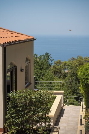 A building with a tiled roof, a balcony, and a view of the sea.