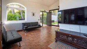 Amplia sala de estar con televisor grande, sofá y ventana con vista a un jardín.