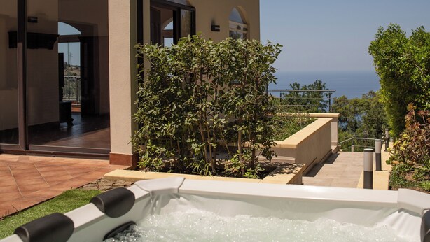 Un área de spa con bañera de hidromasaje, piscina y vistas al mar.
