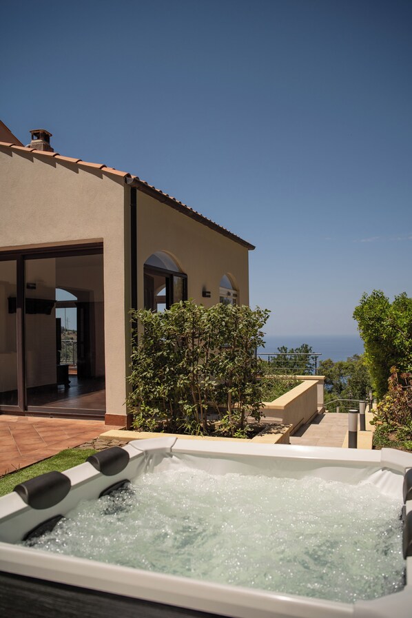 A spa area with a hot tub, a pool, and a view of the sea.