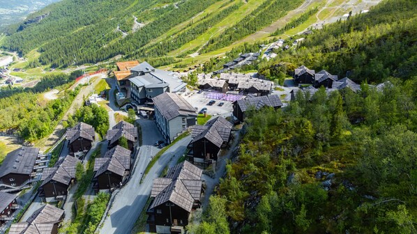 En by belägen i ett bergigt område med traditionella trähus, en central byggnad med ett sluttande tak och en slingrande väg.