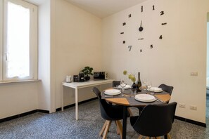 A dining area with a table set for two, a clock on the wall, and a window with blinds. - NEW OPENING: Free Netflix & Wi-Fi at Domus Adriana (Roma)