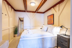 Un dormitorio con cama, mesita de noche, lámpara y un cuadro en la pared.