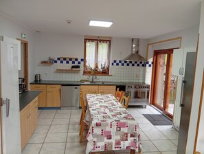 A compact kitchen with a dining table, a stove, and a dishwasher. - L'envers de la Hutte Vacation Rental, Bussang (Bussang)