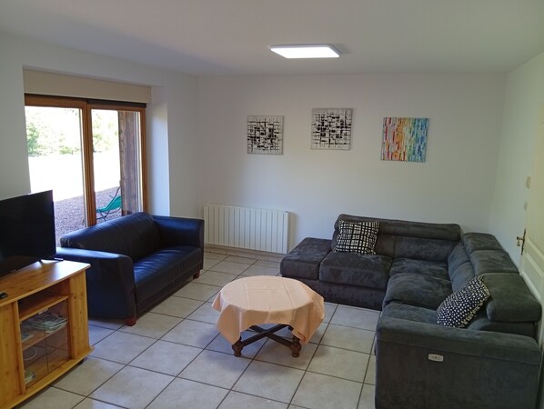 A living room with a TV, two sofas, a small table, and artwork on the walls.