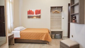 A bedroom with a bed, a hanging garment rack, a small bench, a wall-mounted shelf, and a painting. - Amalia City Rooms (Chios)