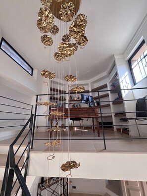 A spacious living area with a piano, bookshelves, and a modern chandelier. - 550-square-meter vacation rental home in Mougins (Mougins)