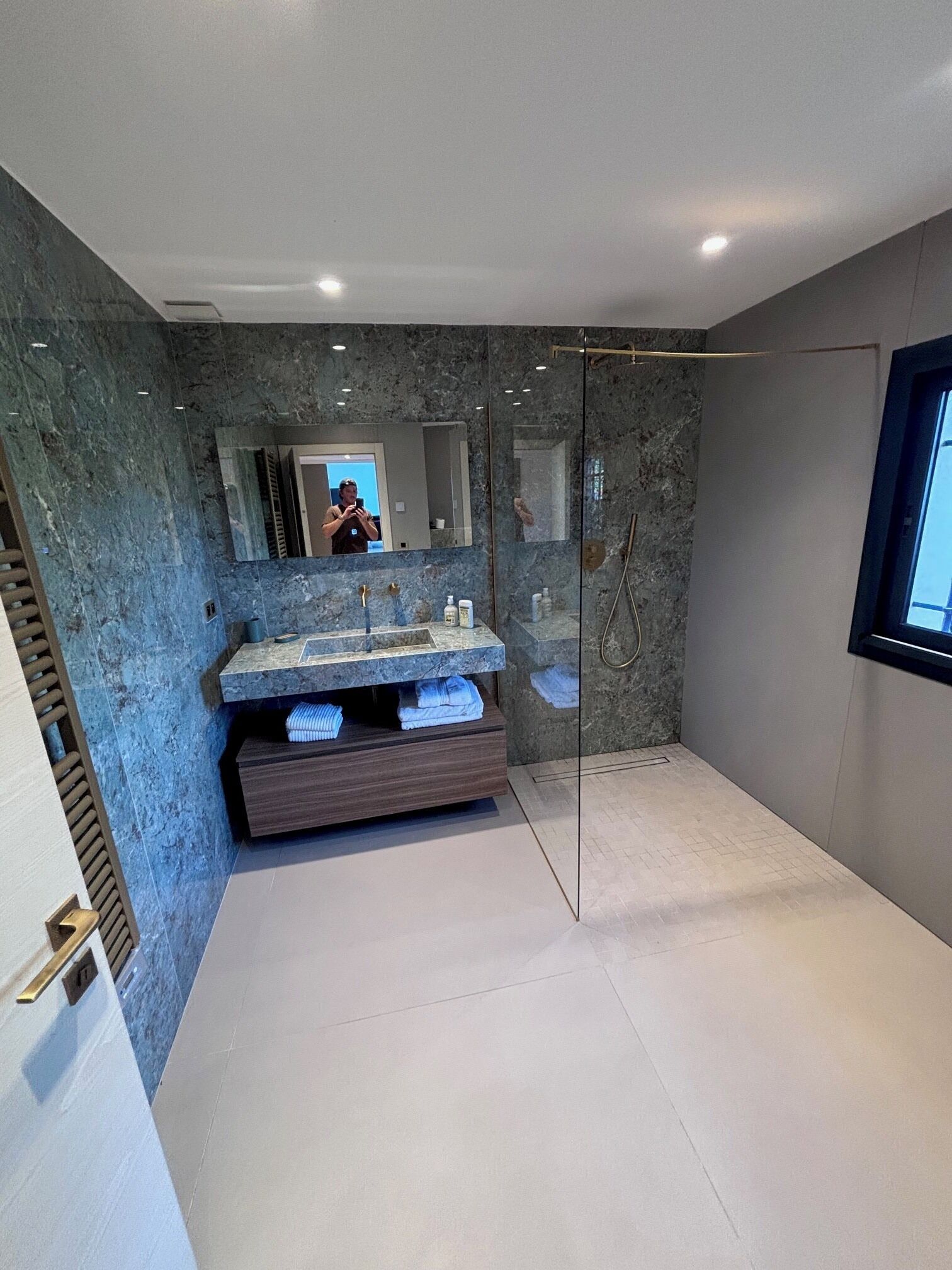 A modern bathroom with a marble vanity, a glass shower enclosure, and a large mirror.