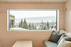 A room with a large window, wooden walls, a bench, and a sofa with cushions. - Mountain cabin near Hafjell with view and hot tub (Øyer)