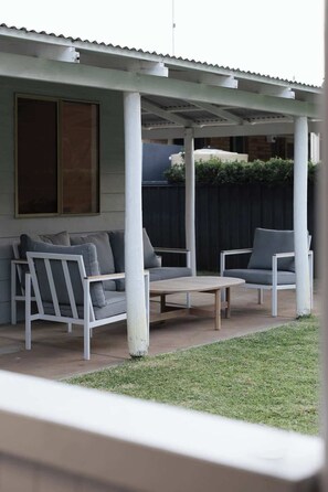A covered patio with a sofa, two chairs, and a table. - Cosy Winter Retreat  Fire, Tea & Sauna (preston beach)