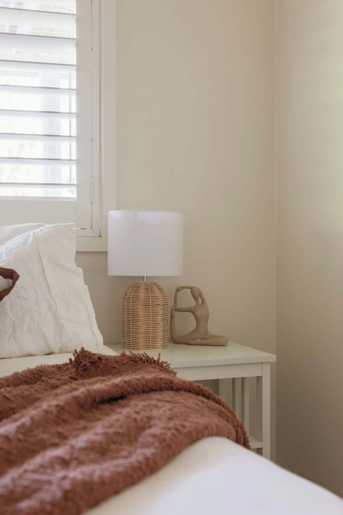 A bedroom with a bed, a bedside table, a lamp, and a pair of shoes.