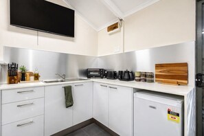 A modern kitchen with a flat-screen TV, a toaster, coffee maker, and a refrigerator. - Cosy Winter Retreat  Fire, Tea & Sauna (preston beach)