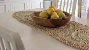 A dining area with a table, a woven placemat, and a bowl of lemons. - Cosy Retreat w/ Sauna & Fire Pit | Golf & Beach (preston beach)