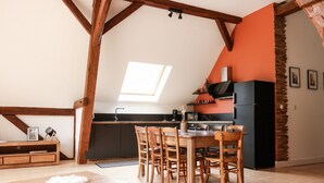 A loft-style room with a dining table, chairs, a kitchen area, and a skylight.