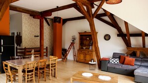 A dining area with a wooden table and chairs, a sofa, and a lamp.