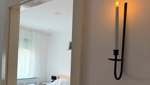 Een slaapkamer met een bed, een nachtkastje en een wandlamp.