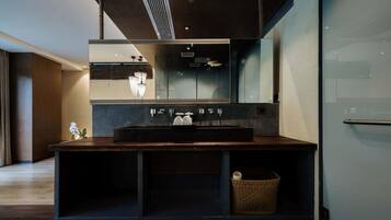 A modern bathroom with a large mirror, dark countertop, and a small wicker basket.