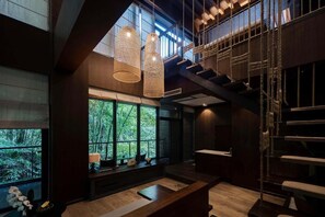 A modern interior with large windows, a staircase, and hanging light fixtures.