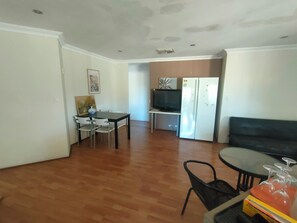 A living room with a dining area, a TV, and a refrigerator.