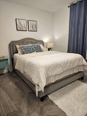 A bedroom with a bed, a nightstand, a lamp, and a window with curtains. - Charming 1-bedroom Basement Suite in Spruce Grove, Alberta (Spruce Grove)