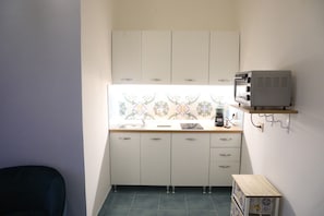 A compact kitchen with white cabinets, a small countertop, a microwave, and a tiled backsplash. - Frontemare (Naples)