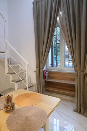 A staircase with a white railing, a wooden table with woven placemats, and a window with curtains. - Frontemare (Naples)