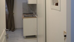 En smal gang med et tekøkken, en skydedør og et lille vindue med en pyntgenstand.