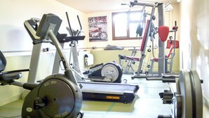 Un gimnàs amb equip d'exercici, incloent una bicicleta el·líptica, una bicicleta estatica i aparells de musculació.