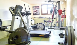 A gym with exercise equipment including an elliptical, a stationary bike, and weight machines. - Pleasant Spot | Dorset Cottage with Stunning Blackmore Vale Views (Buckland Newton)
