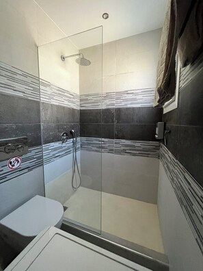 Een moderne badkamer met een glazen douchecabine, een toilet en een handdoekrek.