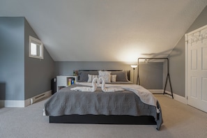 Ein Schlafzimmer mit einem Bett, einem Nachttisch, einer Lampe, einer Kommode und einer Tür.