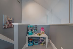Un espace de jeux pour enfants avec un petit ensemble de cuisine, une voiture jouet et une tortue jouet, le tout posé sur une table blanche.
