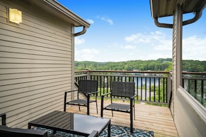 Eine Terrasse mit Blick auf einen See und Wald, ausgestattet mit einem Tisch und Stühlen.