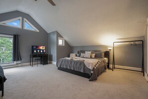 Une chambre à coucher avec un lit, un bureau, une télévision et une fenêtre.