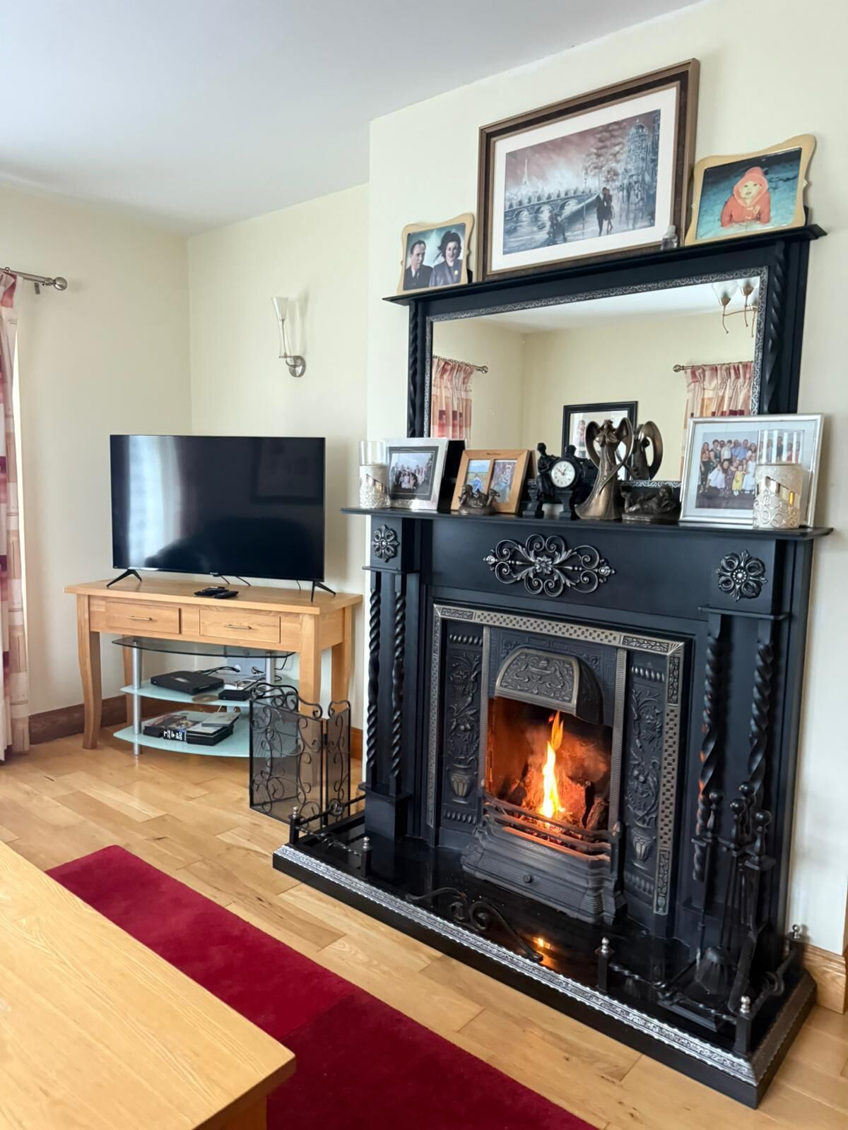 A living room with a fireplace, a television, and a wooden desk.