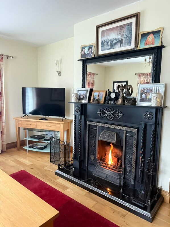 A living room with a fireplace, a television, and a wooden desk.
