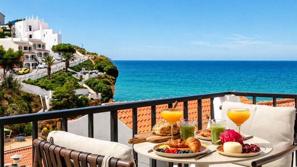 Un balcón con mesa listo para el desayuno y vista al mar.